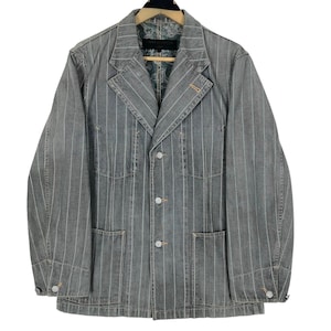 May include: Gray denim blazer with vertical white pinstripes. The jacket features a notched lapel, three front buttons, and two front pockets. The interior lining has a paisley pattern. The jacket is hanging on a wooden hanger.