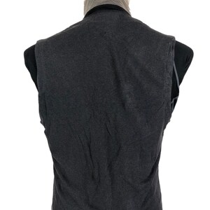 May include: A dark gray vest with a black collar, displayed on a mannequin. The vest appears to be made of a soft, textured fabric. The back of the vest is visible, showing the cut and design.
