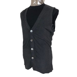 May include: Dark gray vest with a V-neck and four round, silver-colored buttons. The vest is sleeveless and appears to be made of a soft, textured fabric. The vest is displayed on a mannequin.