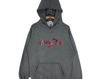 May include: A charcoal gray hoodie with a drawstring hood and a front kangaroo pocket. The hoodie features the text "Black Flys" in a red and black design across the chest. The hoodie is displayed on a wooden hanger.
