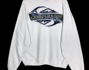 May include: White sweatshirt with a large Quiksilver logo on the back. The logo is a stylized design in shades of blue and black. The sweatshirt has a crew neck and long sleeves.