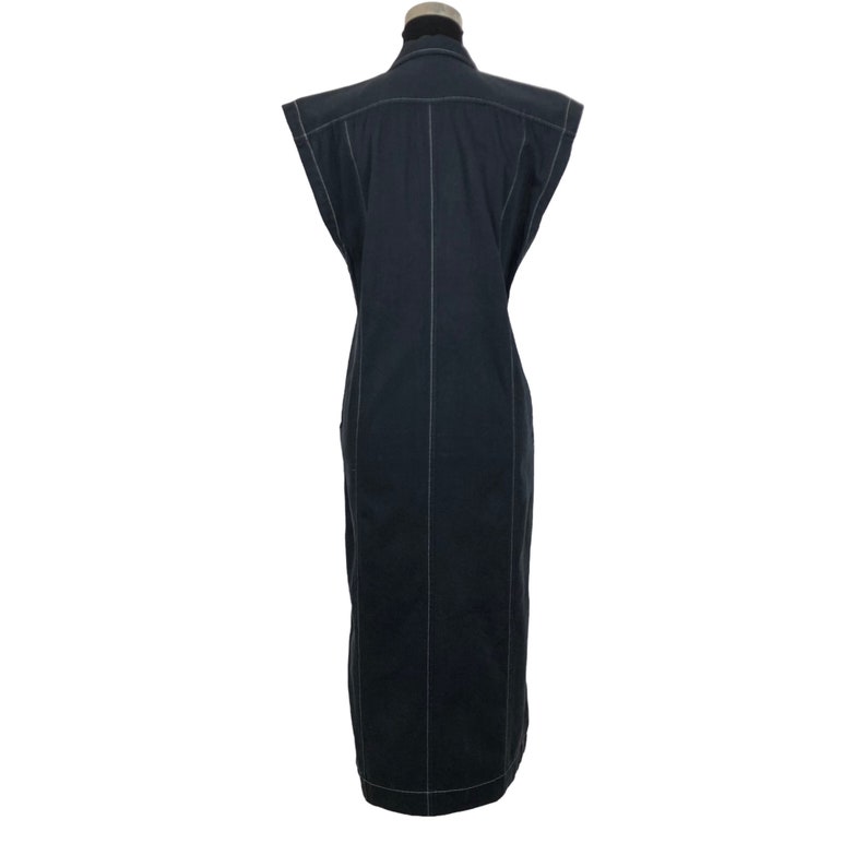 May include: A sleeveless, dark navy blue dress with white stitching details. The dress has a collared neckline and a tailored fit, with vertical seams running down the front and back. The dress is displayed on a mannequin.