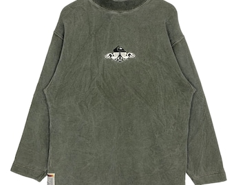 May include: Olive green long-sleeve sweatshirt with a mock neck. The sweatshirt features a small embroidered design on the chest. The garment is hanging on a wooden hanger.