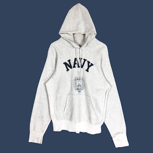 Könnte beinhalten: Ein hellgrauer Kapuzenpullover mit dem Wort "NAVY" in marineblauen Großbuchstaben auf der Brust. Darunter befindet sich ein marineblaues Emblem. Der Kapuzenpullover hat eine Kapuze und eine Vordertasche.
