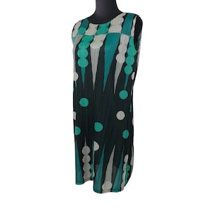 May include: Sleeveless dress with a pleated design. The dress features a pattern of teal, grey, and white circles and vertical lines against a black background. The dress is displayed on a black mannequin.