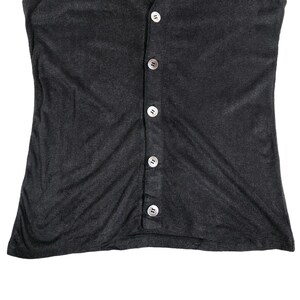 May include: A dark gray, button-down top with a scoop neck. The top has a series of six round, pearlescent buttons down the center. The fabric appears to be a soft, lightweight material.