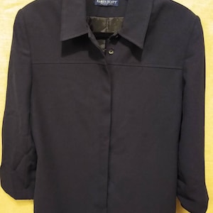 May include: A navy blue long-sleeved button-up shirt with a collar. The shirt has a label that reads "Karen Scott Petite".