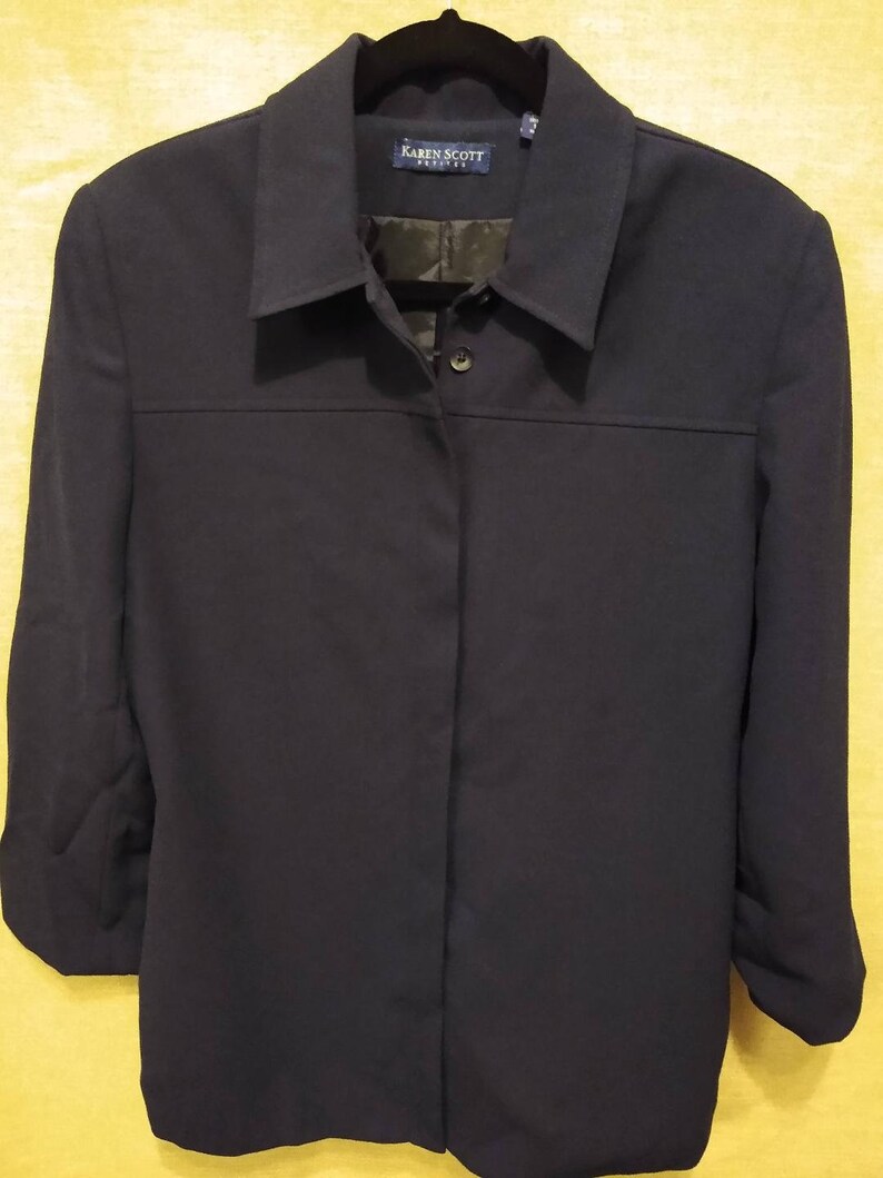 May include: A navy blue long-sleeved button-up shirt with a collar. The shirt has a label that reads "Karen Scott Petite".