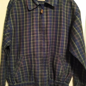 May include: A blue, green, and purple plaid zip-up jacket with a brown button on the zipper pull.