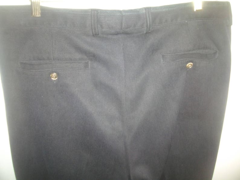 May include: A pair of dark gray dress pants with a subtle pinstripe pattern. The pants have two pockets on the back, each with a button closure.