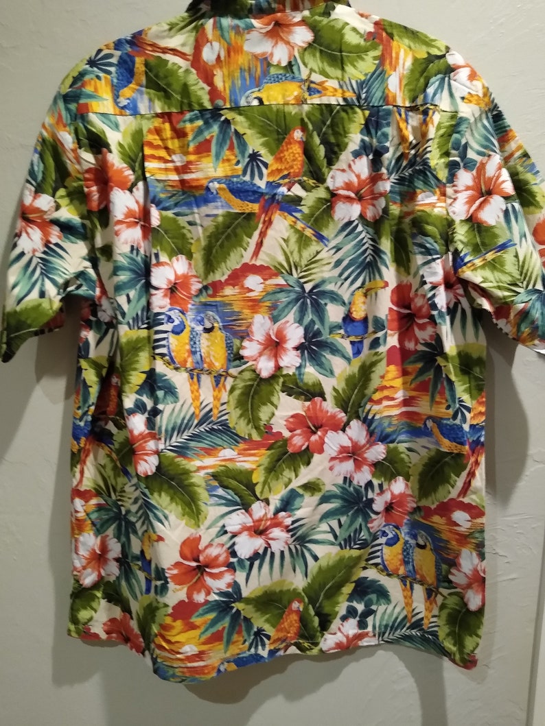 May include: A short-sleeved button-down shirt with a tropical print featuring parrots, flowers, and palm leaves in shades of green, blue, red, yellow, and orange.