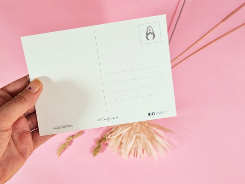 May include: A white postcard with a simple black and white illustration of a penguin on the top right corner. The postcard has lines for writing a message and the text "Lilies" and "www.lilies-berlin.com" at the bottom. The text "fb thelilies" is in the bottom right corner.