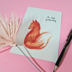 May include: A white card with a hand-drawn illustration of a red fox sitting with its tail curled around its body. The text "du bist gro&szlig;artig" is written in black ink on the card.