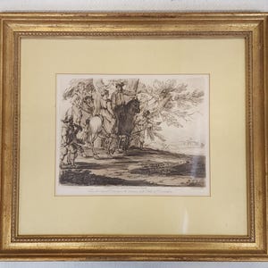 May include: An antique framed print with a gold-colored wooden frame. The print depicts a historical scene with figures on horseback and in period clothing. The artwork is in black and white, with fine details and shading. The print is mounted on a cream-colored mat.