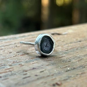 May include: A silver earring with a black agate stone. The stone has a natural, druzy finish.