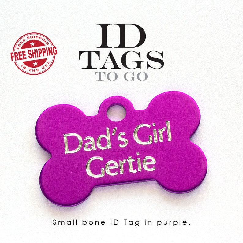 Puede incluir: Etiqueta de identificaci&oacute;n para mascotas de color morado en forma de hueso con el texto "Dad's Girl Gertie" grabado en letras plateadas.