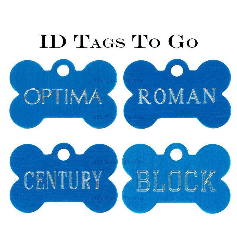 Puede incluir: Cuatro etiquetas de identificaci&oacute;n para perros de hueso azul con letras plateadas. Las etiquetas dicen "OPTIMA", "ROMAN", "CENTURY" y "BLOCK".