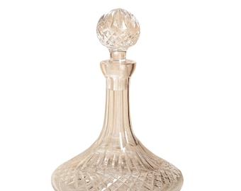 May include: A clear glass decanter featuring a wide, rounded base and a slender neck. The body and the spherical stopper are decorated with a detailed diamond-cut pattern, creating a textured surface that reflects light across the entire vessel.