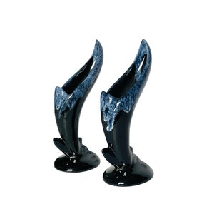May include: A pair of black and blue ceramic vases with a unique, abstract design. The vases are tall and slender, with a flared opening at the top. They are perfect for displaying flowers or other decorative items.