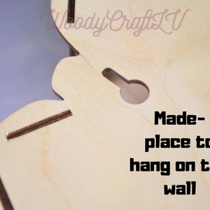 May include: Close-up of a light wood cutout with a hole for hanging. The text "Made-place to hang on the wall" is printed on the wood.