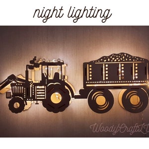 May include: A wooden tractor and trailer night light with a black silhouette and a string of lights inside. The trailer is filled with a grain. The text "night lighting" is above the tractor and "Woody Crafts LV" is below the trailer.