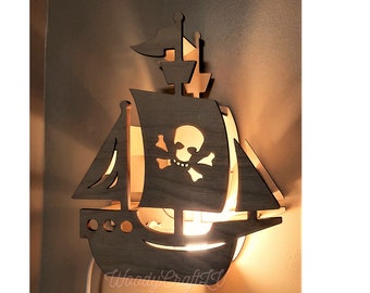 May include: A wooden pirate ship wall lamp with a skull and crossbones design. The lamp is lit and casts a warm glow.