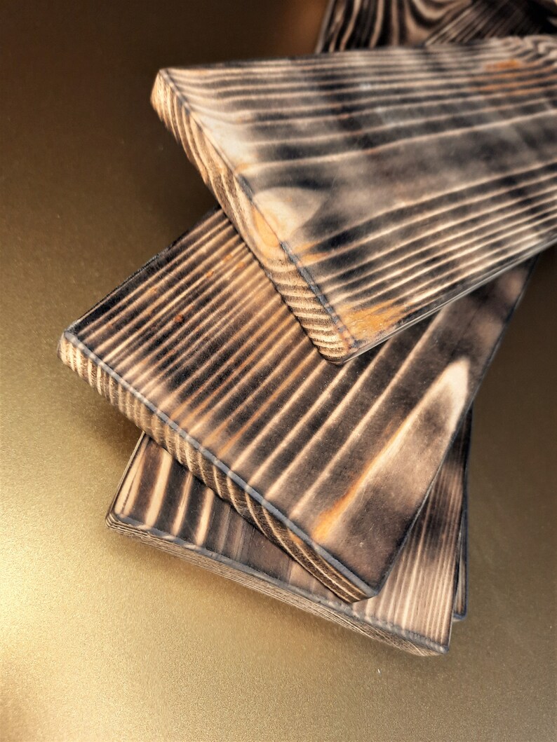 May include: Three wooden boards with a dark brown, charred finish. The boards are stacked on top of each other, with the top board slightly offset from the bottom two.