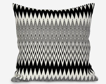 Könnte beinhalten: Ein rechteckiges Dekokissen mit einem schwarzen und weißen Chevron-Muster. Das Kissen hat einen weißen Hintergrund mit schwarzen Chevron-Streifen.