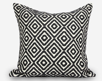May include: Square cushion with a black and white geometric diamond pattern. The cushion has a soft, textured appearance and is designed for decorative use on a sofa or bed. The design features a repeating pattern of black diamonds on a white background.