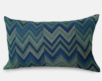 Könnte beinhalten: Ein blaues und grünes Kissen mit Chevron-Muster. Das Kissen ist rechteckig und hat einen weichen, strukturierten Stoff.
