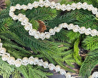 May include: A decorative garland featuring a repeating pattern of smooth, cream-colored faux pearls interspersed with small, sparkling silver-toned crystal accents. The strand is flexible and arranged in a continuous, undulating wave-like design.