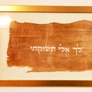 K&ouml;nnte beinhalten: Ein gerahmtes St&uuml;ck Pergament mit hebr&auml;ischer Schrift in Wei&szlig; auf braunem Hintergrund. Die Schrift lautet "כִּי אָבְלִי הַשְּׁקוֹלָה"