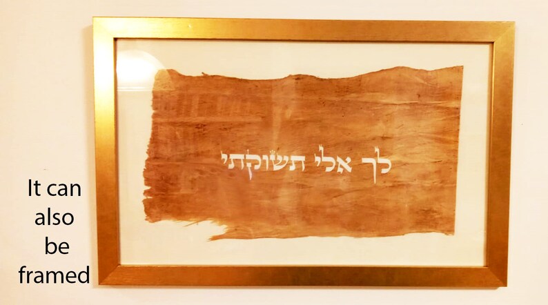 K&ouml;nnte beinhalten: Ein gerahmtes St&uuml;ck Pergament mit hebr&auml;ischer Schrift in Wei&szlig; auf braunem Hintergrund. Die Schrift lautet "כִּי אָבְלִי הַשְּׁקוֹלָה"