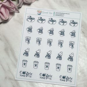 May include: A sheet of stickers featuring illustrations of a cartoon character drinking coffee. The stickers are white with black outlines and blue accents. The stickers include various poses of the character, including sitting in a coffee cup, holding a coffee cup, and drinking from a coffee cup. The sheet also includes three stickers with the text "Coffee Time" in a stylized font.