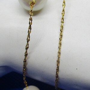 May include: A gold chain necklace with three white pearls. The chain is a twisted rope style.