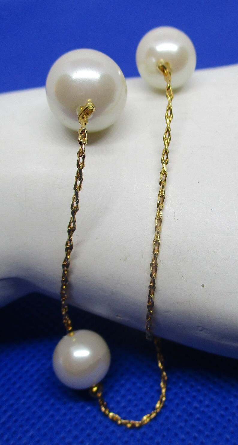 May include: A gold chain necklace with three white pearls. The chain is a twisted rope style.