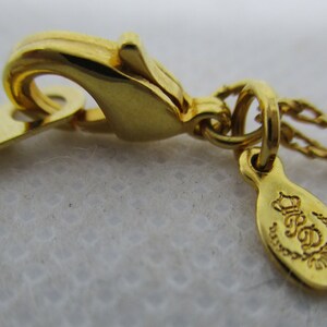 May include: Gold-tone chain necklace with a lobster clasp and a small oval tag with the inscription "R.S.D. Designs" in a cursive font.
