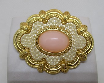 Spilla vintage Avon degli anni '80, mai indossata, con perla cabochon rosa, pietra preziosa ovale rosa, perla sintetica, metallo color oro con bordo smerlato.
