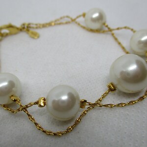 May include: A gold chain bracelet with five large white pearl beads.