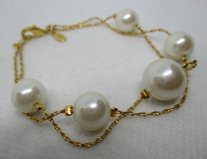 May include: A gold chain bracelet with five large white pearl beads.