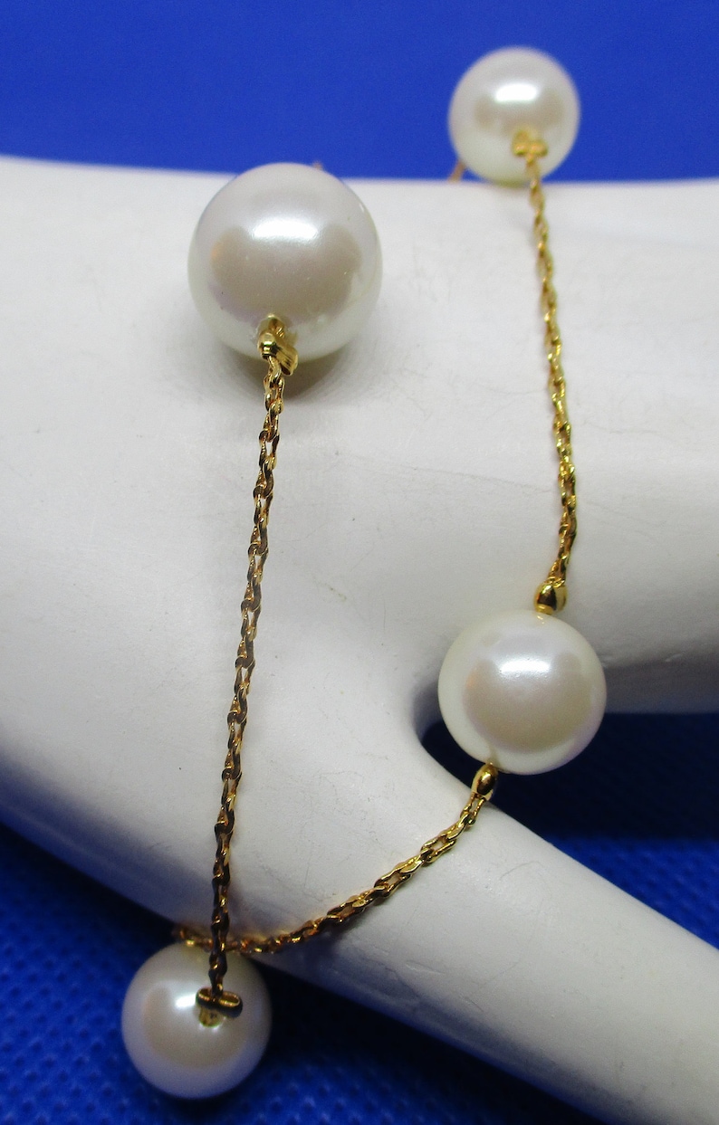 May include: A gold chain bracelet with four white pearls. The pearls are different sizes and are evenly spaced along the chain.
