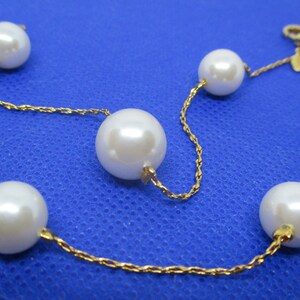 May include: A gold chain bracelet with five white pearls. The chain is a delicate rope style.