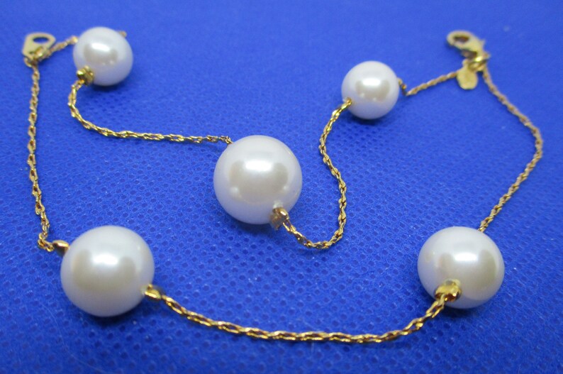 May include: A gold chain bracelet with five white pearls. The chain is a delicate rope style.