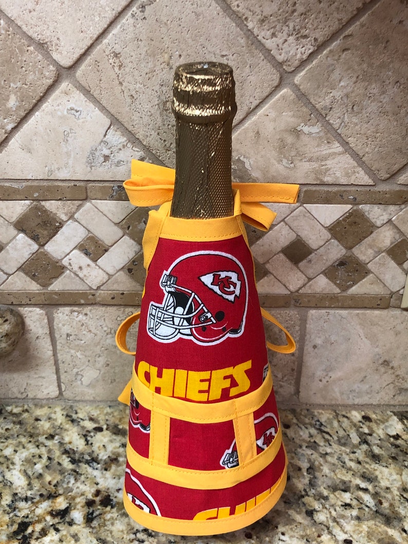 Może przedstawiać: Czerwono-ż&oacute;łty pokrowiec na butelkę z logo Kansas City Chiefs i napisem "CHIEFS".
