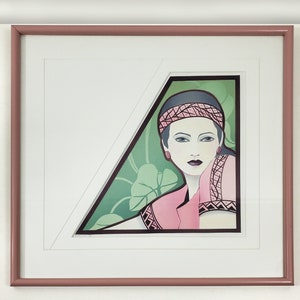 May include: A framed print of a woman with dark hair wearing a pink headband and a pink and black patterned jacket. The background is a green and white geometric pattern.