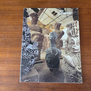 May include: A white ceramic mug with a black handle and the text "But First, Coffee" in a bold, black font. The mug is set against a neutral background, highlighting its simple design.