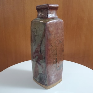 Peut inclure: Un vase en céramique brun et vert de forme carrée avec une surface texturée.