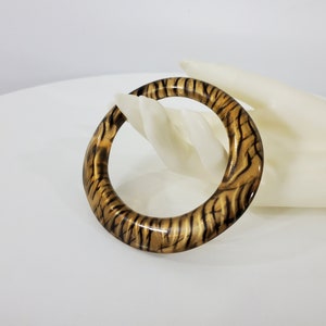 May include: A brown and black bangle bracelet with a tiger stripe pattern.