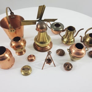Peut inclure: Une collection de miniatures de cuisine en cuivre et en laiton, comprenant un moulin à vent, un seau, une théière, un pichet et divers autres objets.