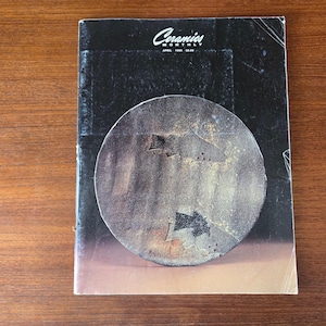 Peut inclure: Une ancienne édition du magazine "Ceramics Monthly". La couverture présente une œuvre d'art circulaire et texturée dans des tons gris et marron sur un fond noir. Le titre du magazine est en blanc, avec la date de publication visible.